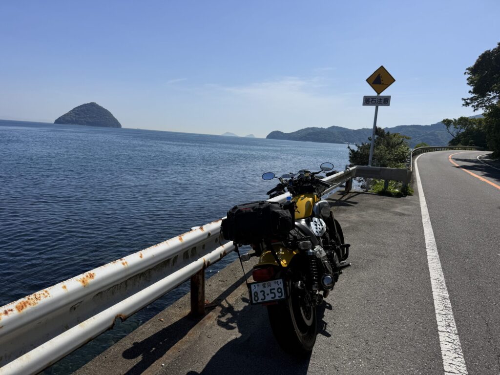 青い海と青い空をバックに海岸線の道路沿いに停車するバイク
