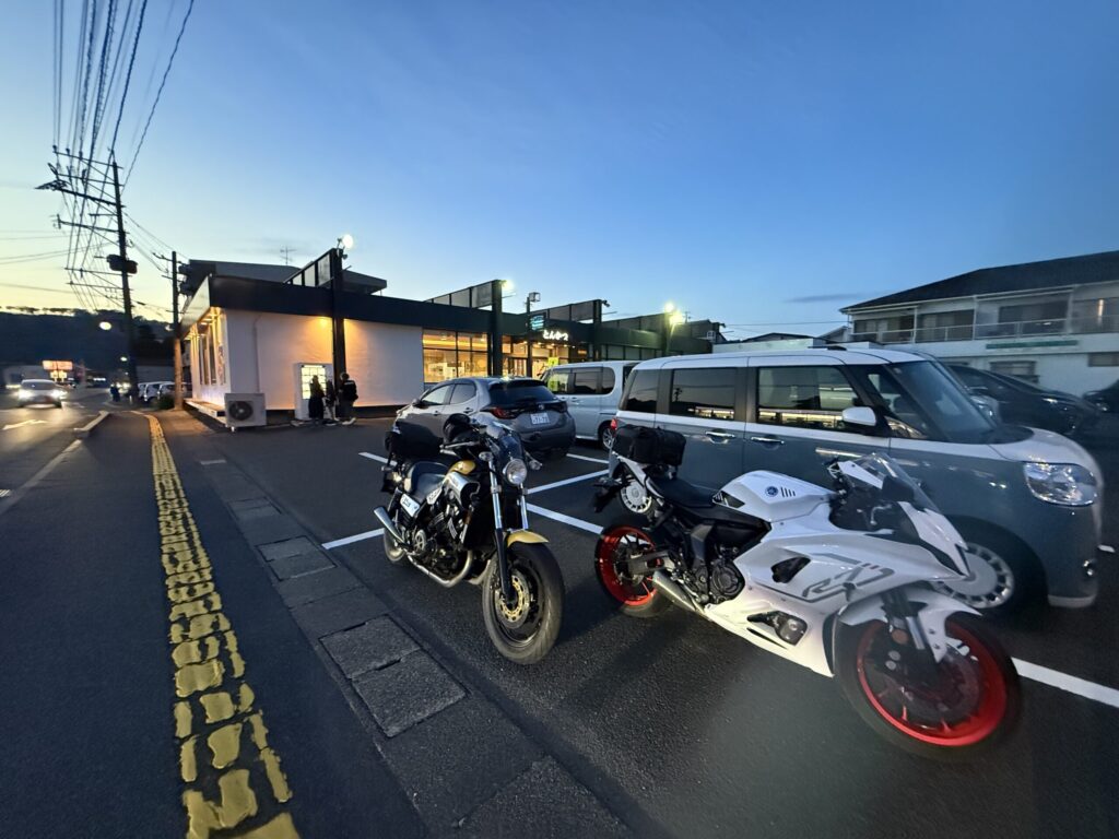 夕暮れ時のかつ弘佐伯本店の駐車場に並んで停車するVMAX1200と白いバイク